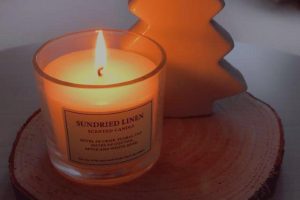sundried linen scented candle lit in wooden log