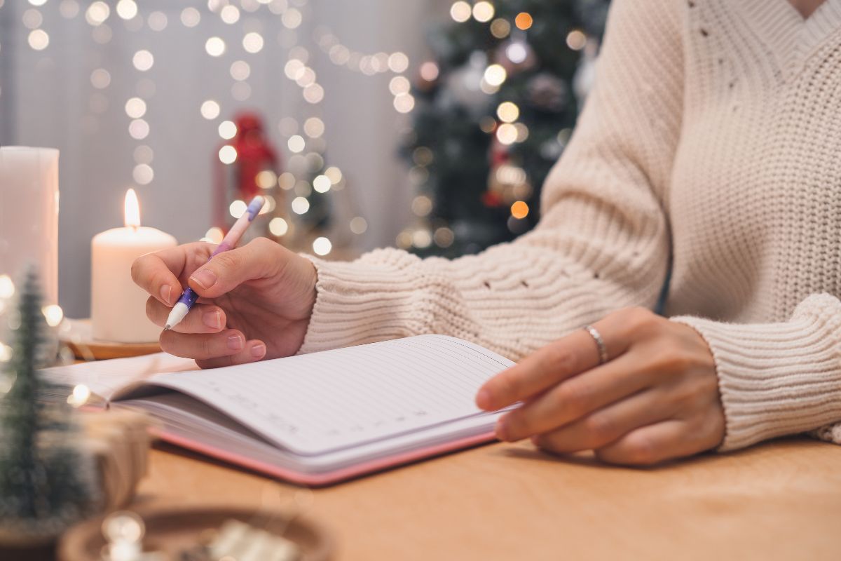 woman writing christmas story in notebook