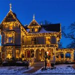 "Victorian home decorated with warm white holiday lights set against a twilight sky."