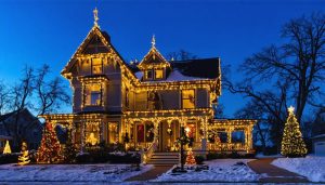 "Victorian home decorated with warm white holiday lights set against a twilight sky."