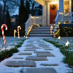Low-angle dusk photo of candy cane–striped solar light stakes lining a snow-covered walkway, with star-shaped solar lights glowing in the lawn and a softly blurred house and evergreens behind.
