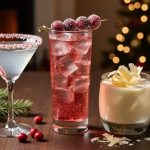 Trio of festive vodka cocktails—peppermint with a candy cane rim, sparkling cranberry with sugared cranberries, and creamy white chocolate with shaved curls—on a dark wooden table with evergreen sprigs and blurred Christmas lights in the background.